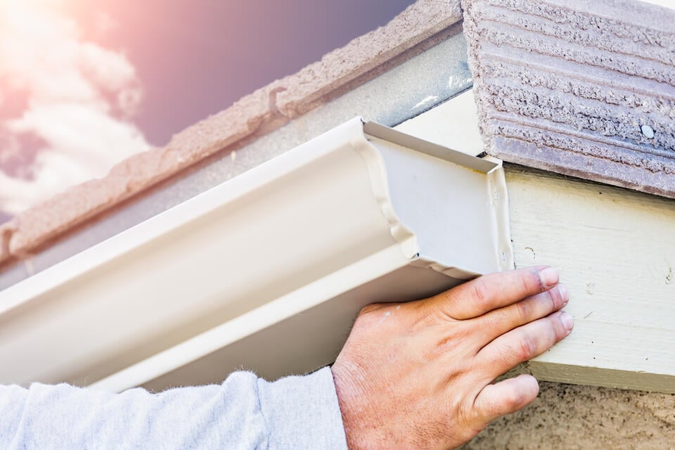 k style gutters-close up of a man installing k style gutters on a home