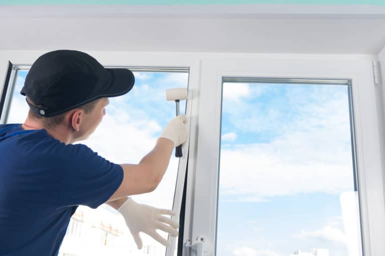 window energy ratings man installing window with white gloves and hammer