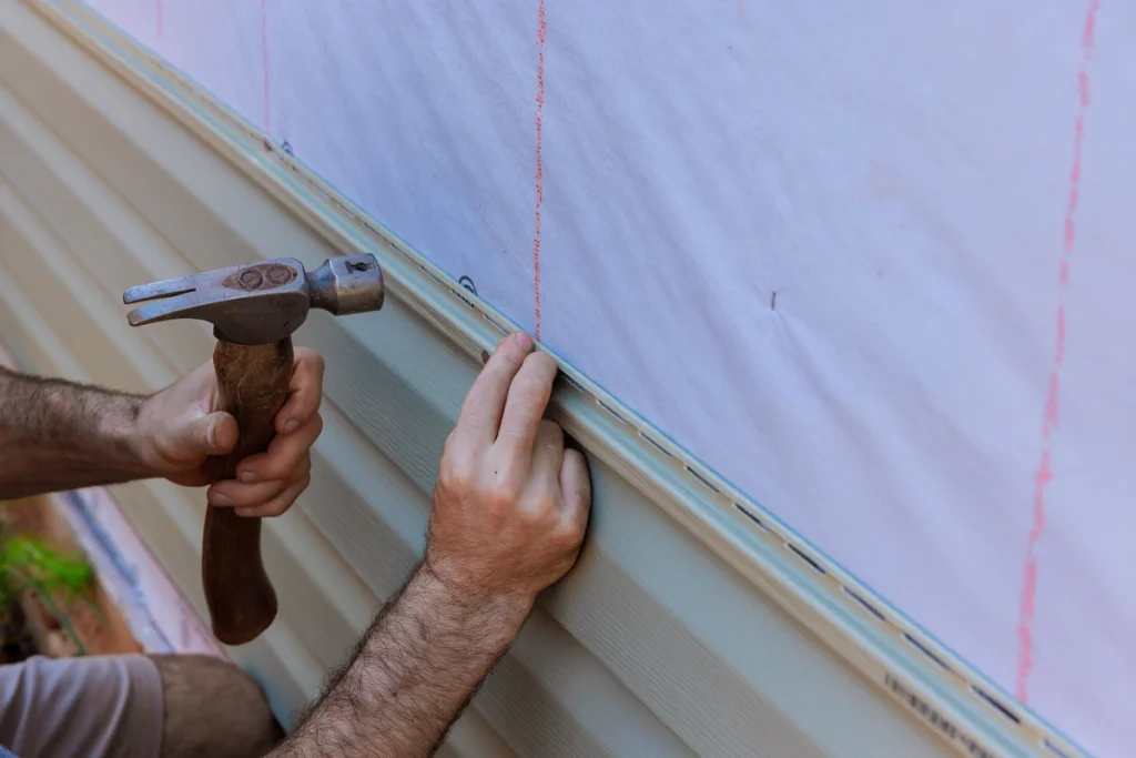 nailing new vinyl siding panels onto home