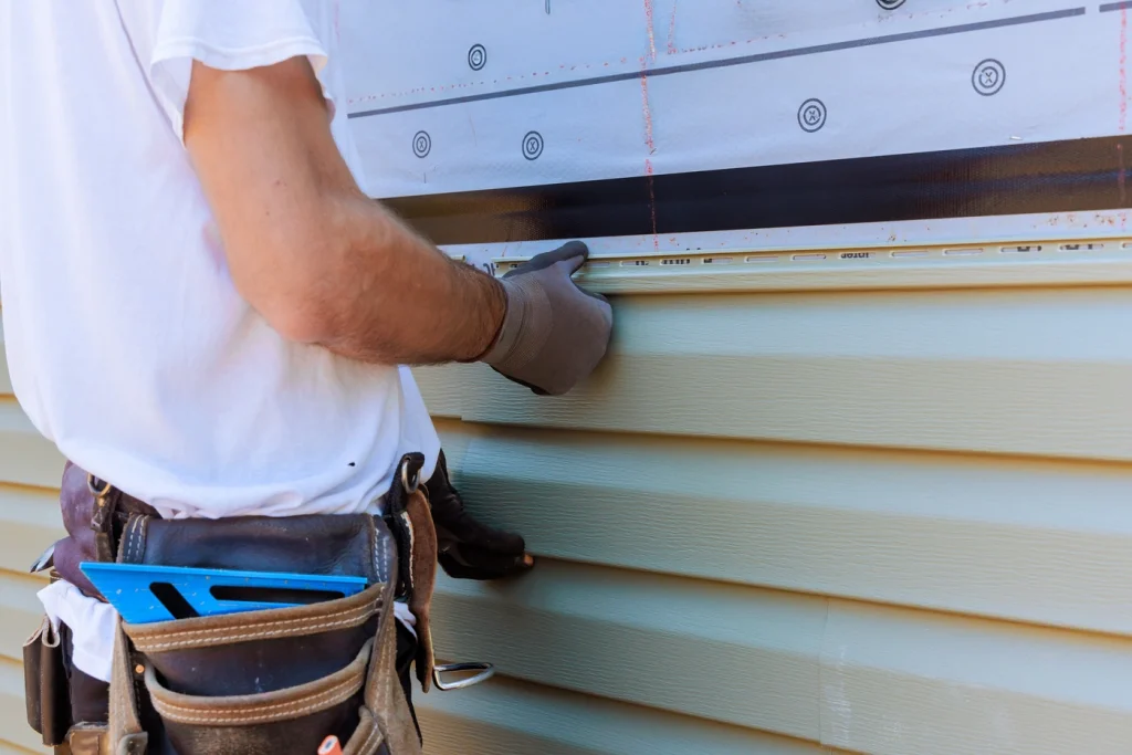 close up view of siding contractor installing beige neutral vinyl siding