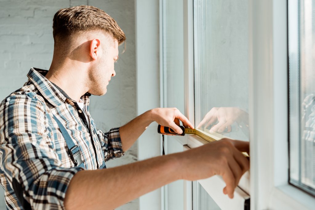 close up of homeowner measuring replacement windows in home