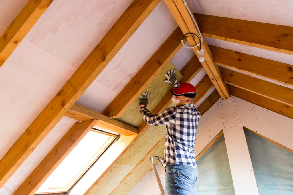 technician installing insulation in the interior part of a home roof