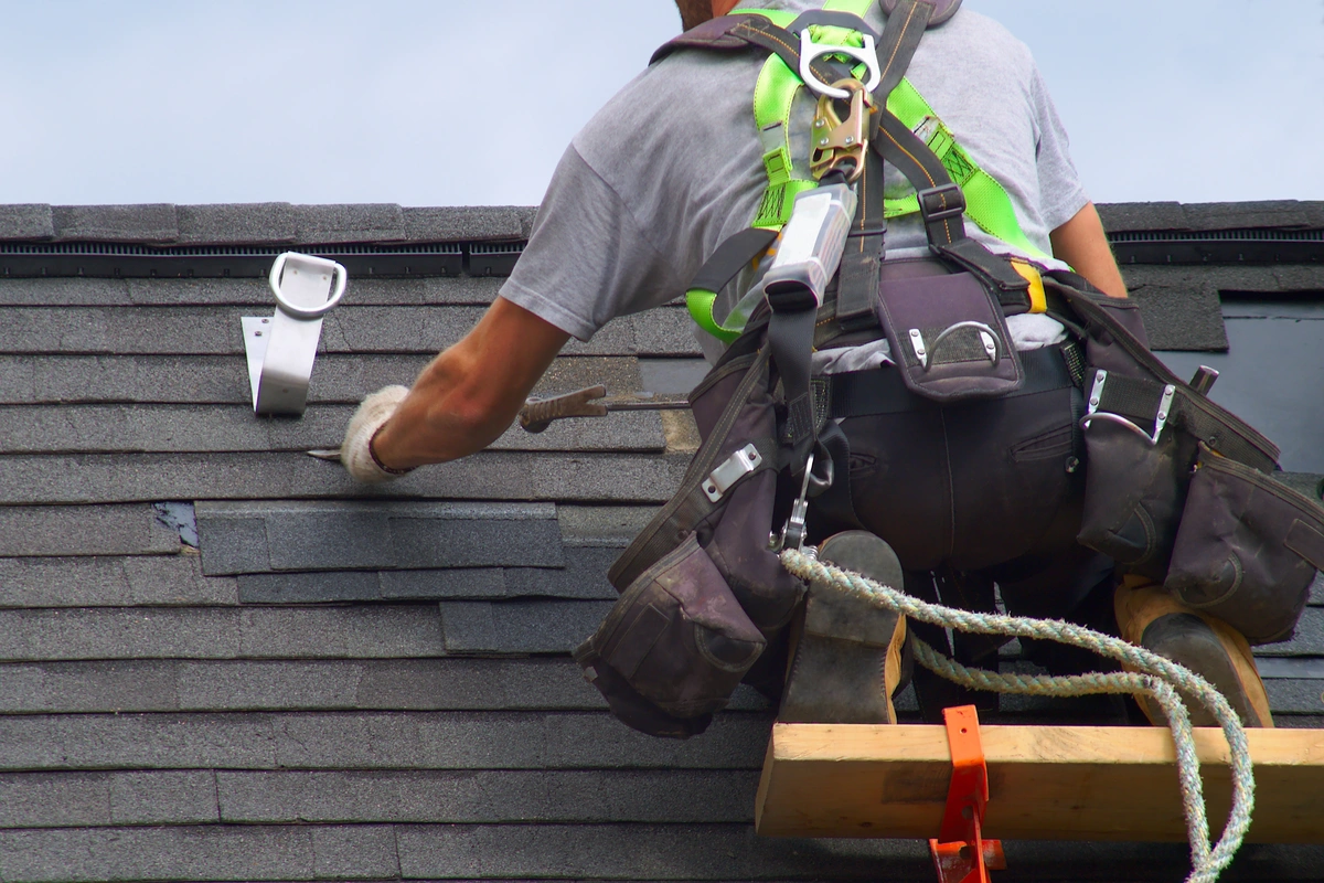 roof tech working on black shingles on a home room
