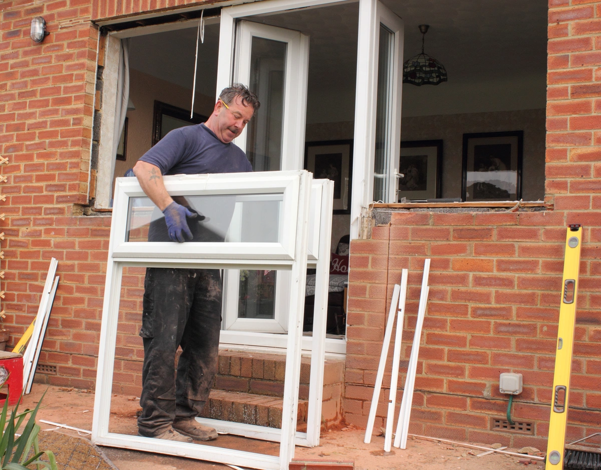 man holding window pane replacements hes about to install