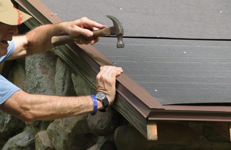 roof drip edge-close up of a man using a hammer to install drip edge materials