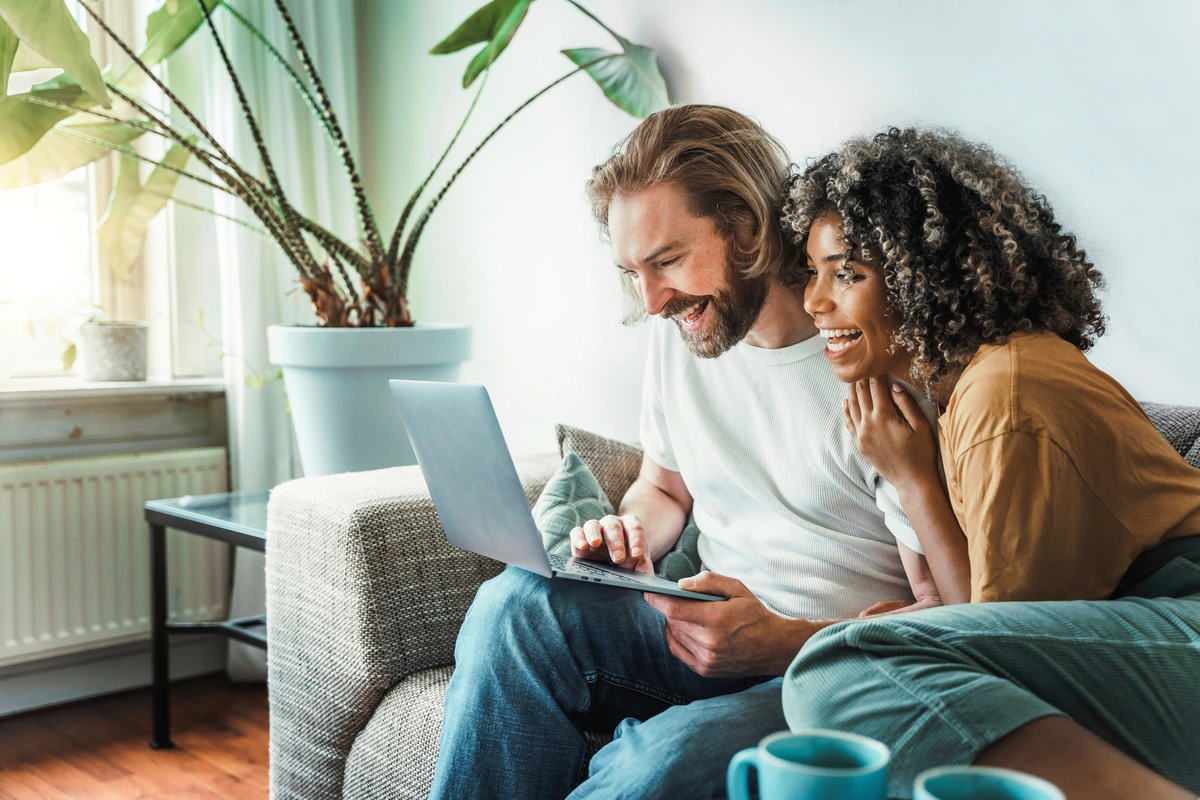 couple smiling while looking at computer