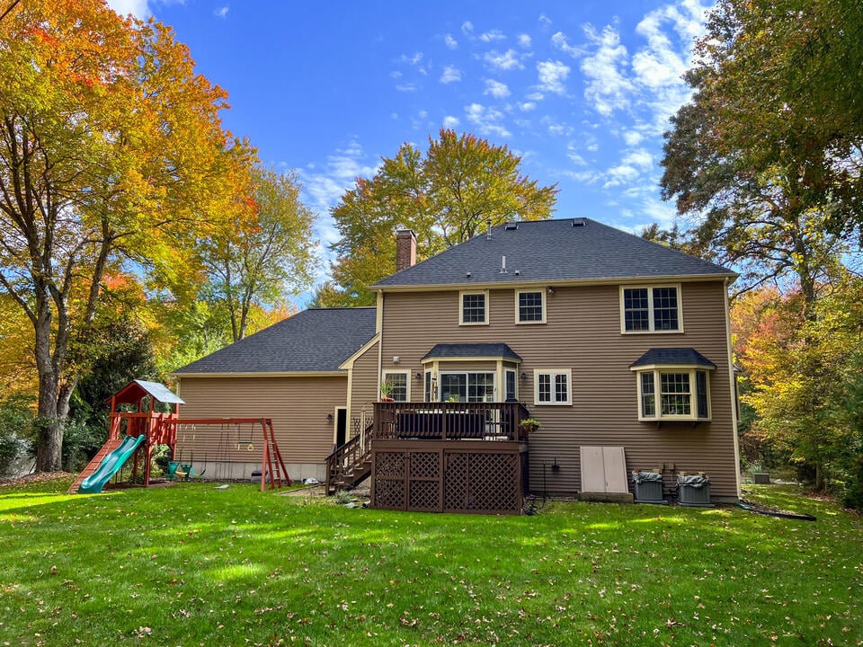 roof design-hip roof style on a brown sided house with play set in backyard