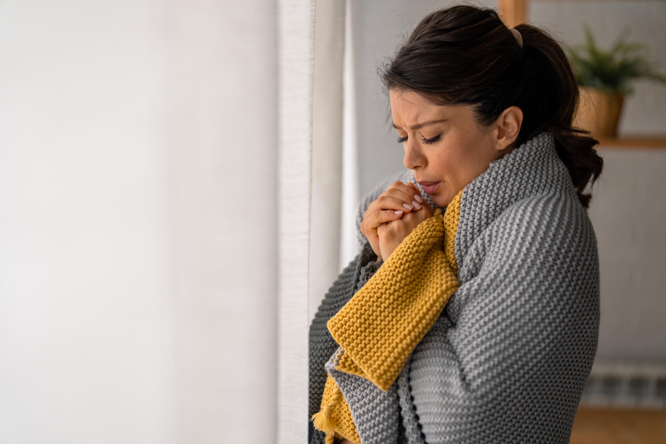 thermal bridging-woman wrapped in blanket freezing because of cold pockets in house