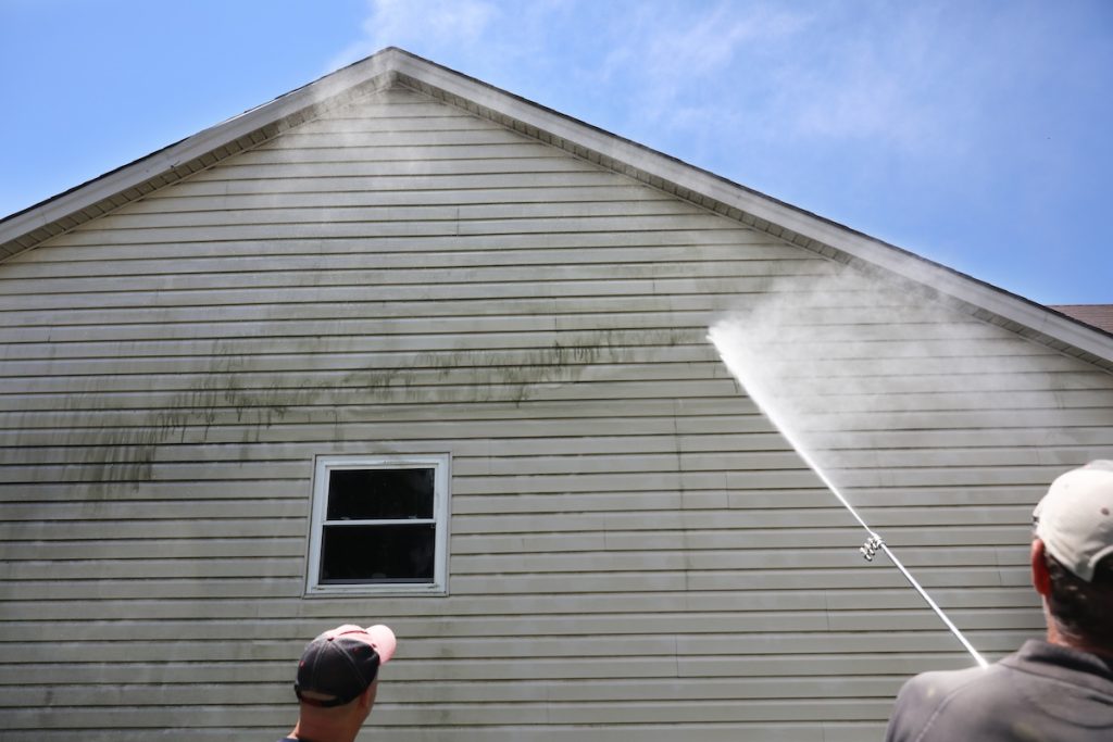 dirty siding being cleaned with power washer