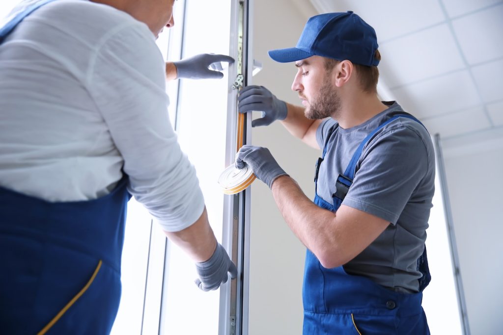 Construction worker with trainee installing window in house