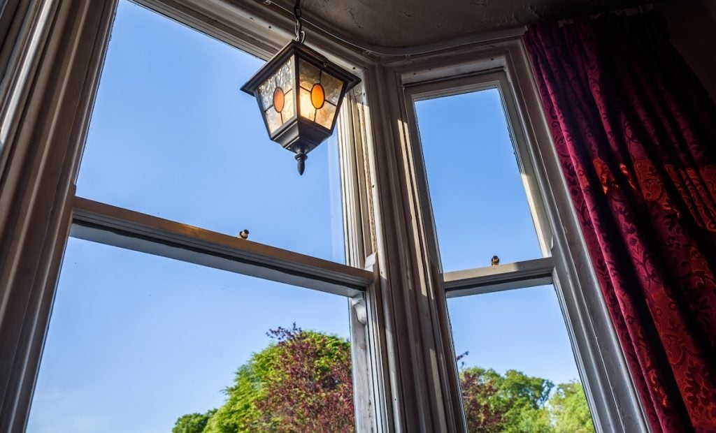 A traditional British pub window with old fashioned lamp and red velvet curtains.