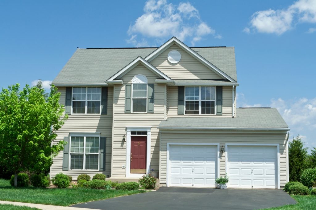 insulated vinyl siding Modern vinyl sided single family home in suburban Maryland. House has two car garage, driveway and red door.