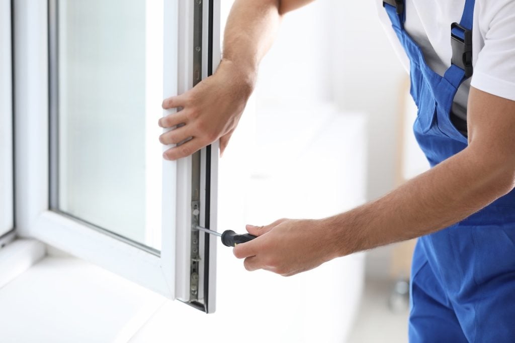 window warranty Construction worker repairing plastic window with screwdriver indoors, closeup