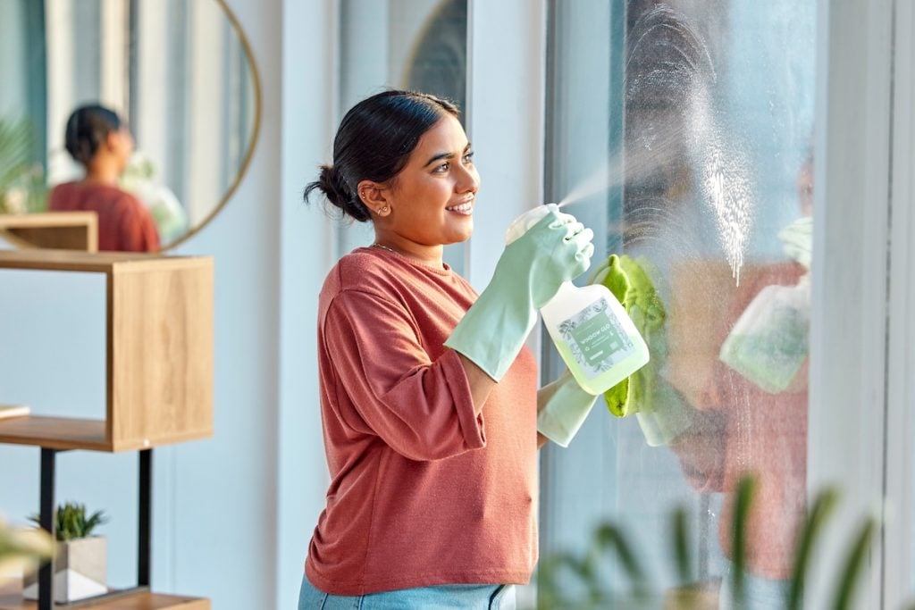 Woman, cleaning and spray product of a cleaner washing a window with a smile in home. Happy working maid use a home hygiene bottle and cloth to disinfect the house furniture with a sanitizer bottle. what is the best homemade window cleaning solution