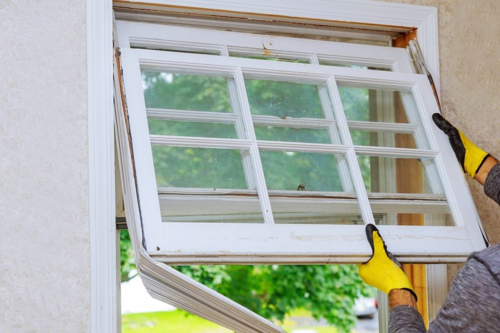 replace broken window Worker hand removing old window replacing the old wooden window,