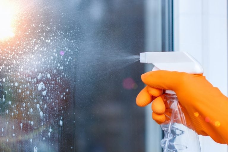 Worker cleans the Windows with spray in the house .