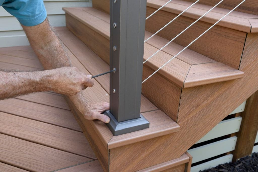 deck railing man installing grey metallic wires