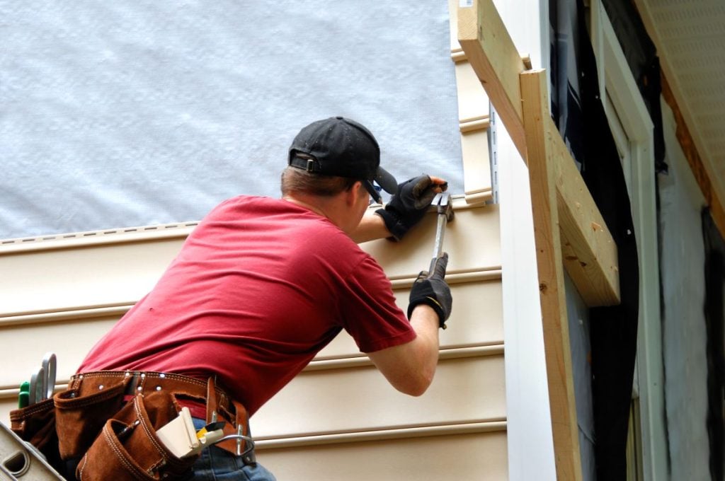 low maintenance siding worker using hammer