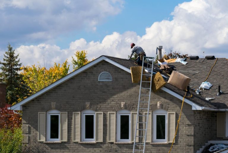roof installation worker on top of brown shingles