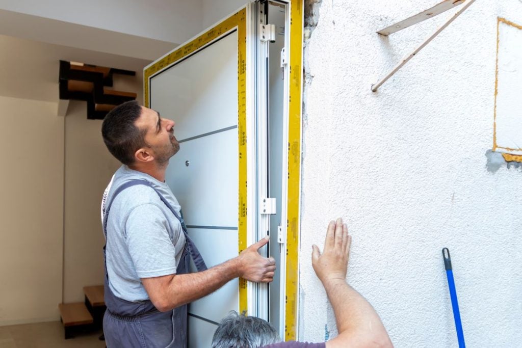 white door security worker replacing door inside house