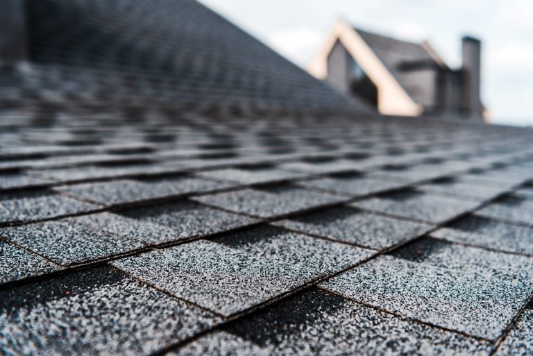 factors influencing roof lifespan selective focus of grey shingles on rooftop of building