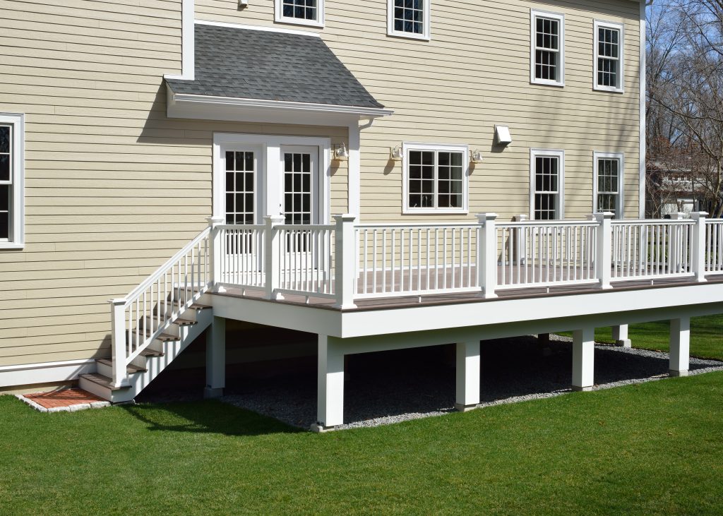 james hardie siding warranty New composite deck. White veranda and railing posts, brown boards, elevated above ground. Showing support frame and gravel under porch.