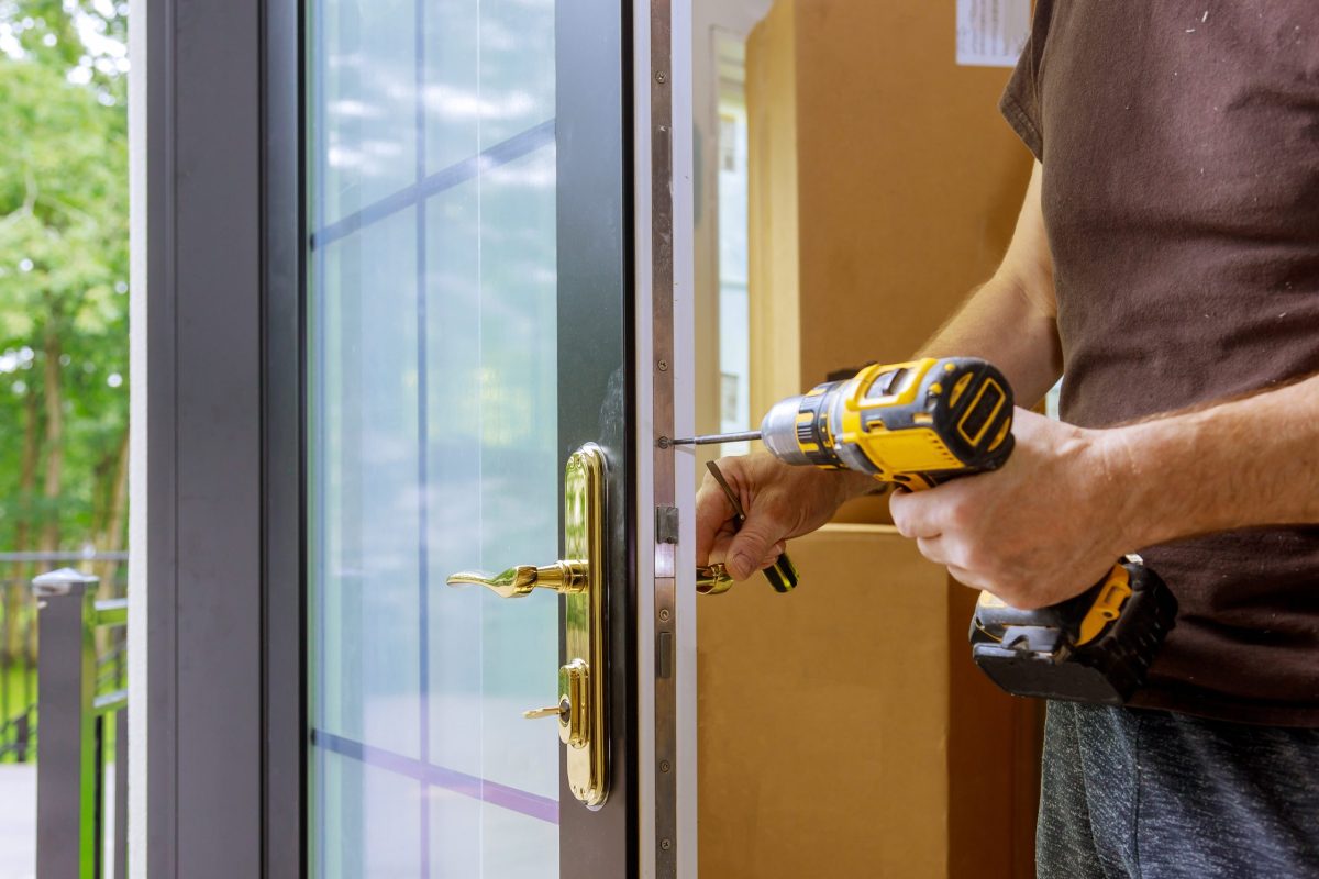 door replacement gaithersburg Install the door handle with a lock, Carpenter tighten the screw, using an electric drill screwdriver, close-up.